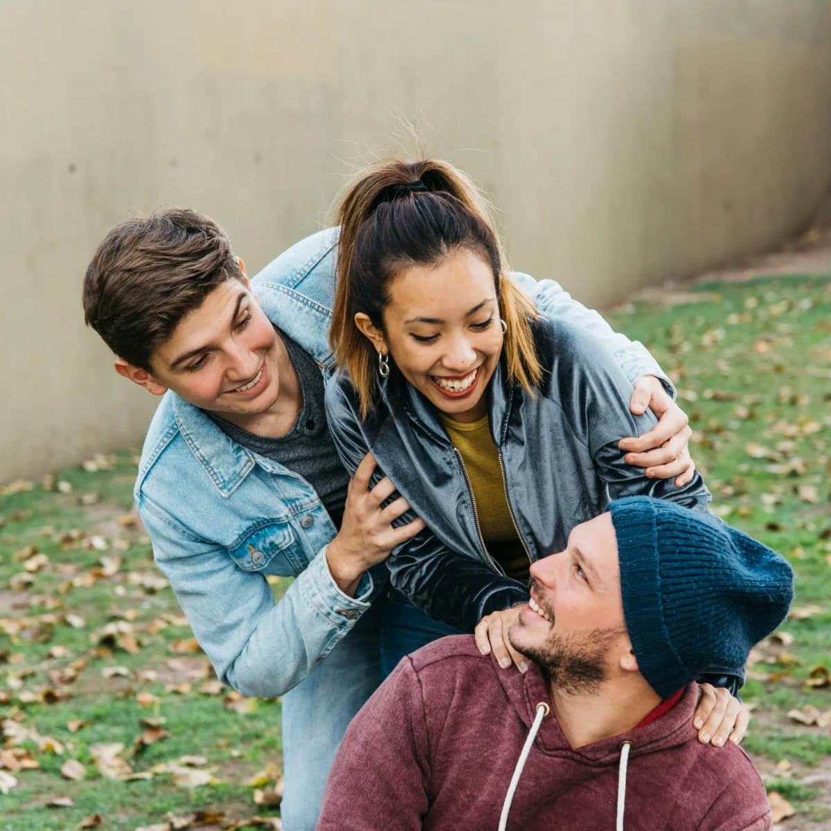 Three friends laughing outdoors, representing peer support and connection in recovery