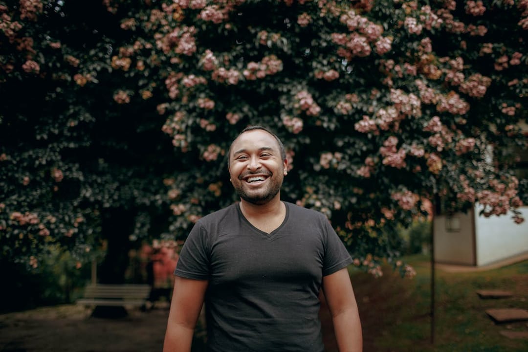 Free A man in a black shirt smiles in front of a tree Stock Photo