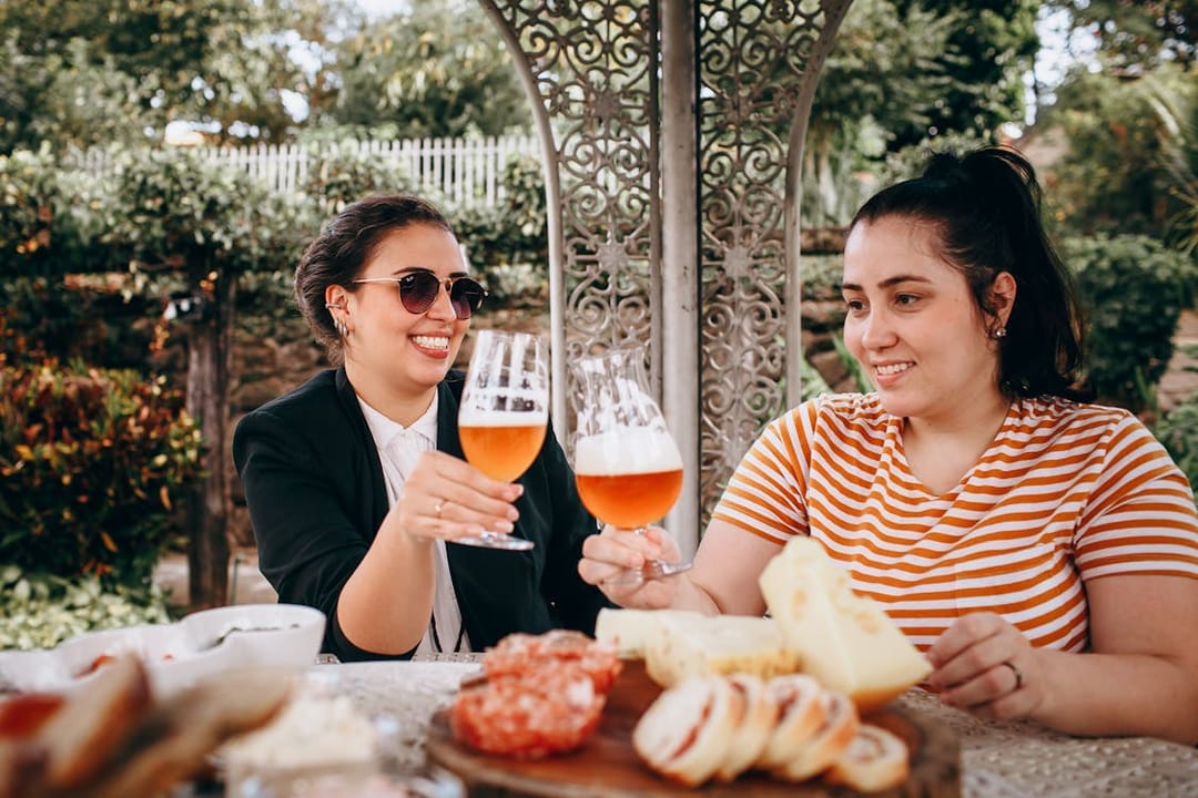 Free Two women toasting with beer at an outdoor table Stock Photo