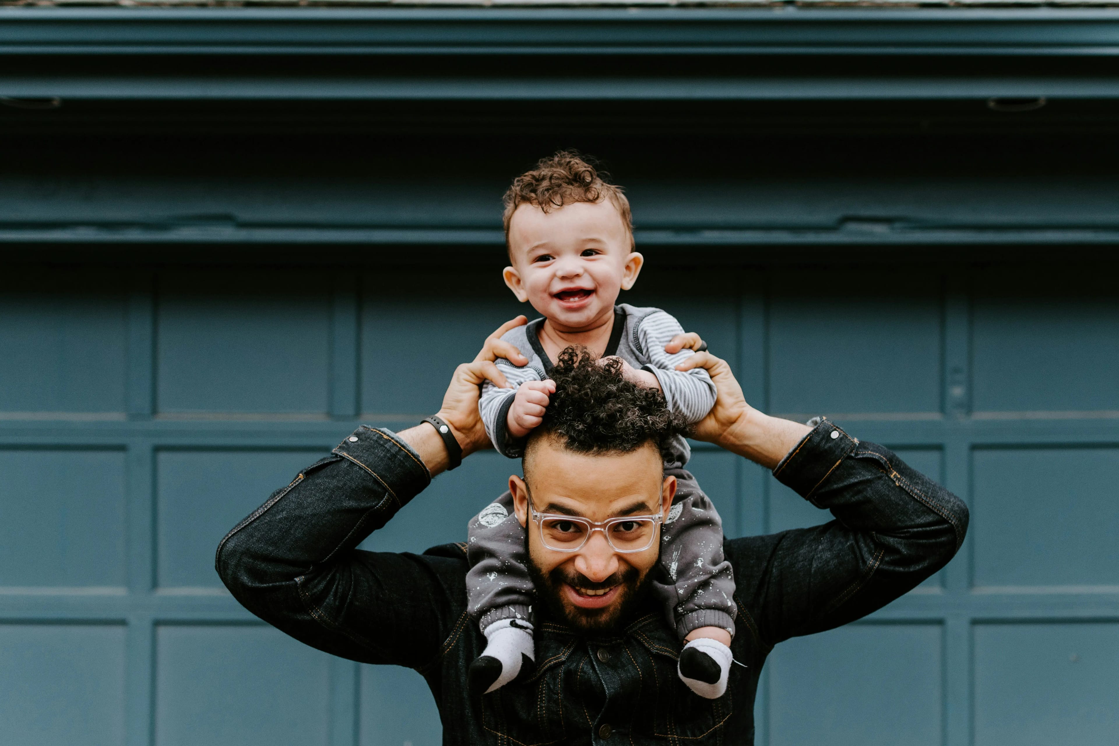 Father with baby on his shoulders, smiling representing family healing in addiction recovery